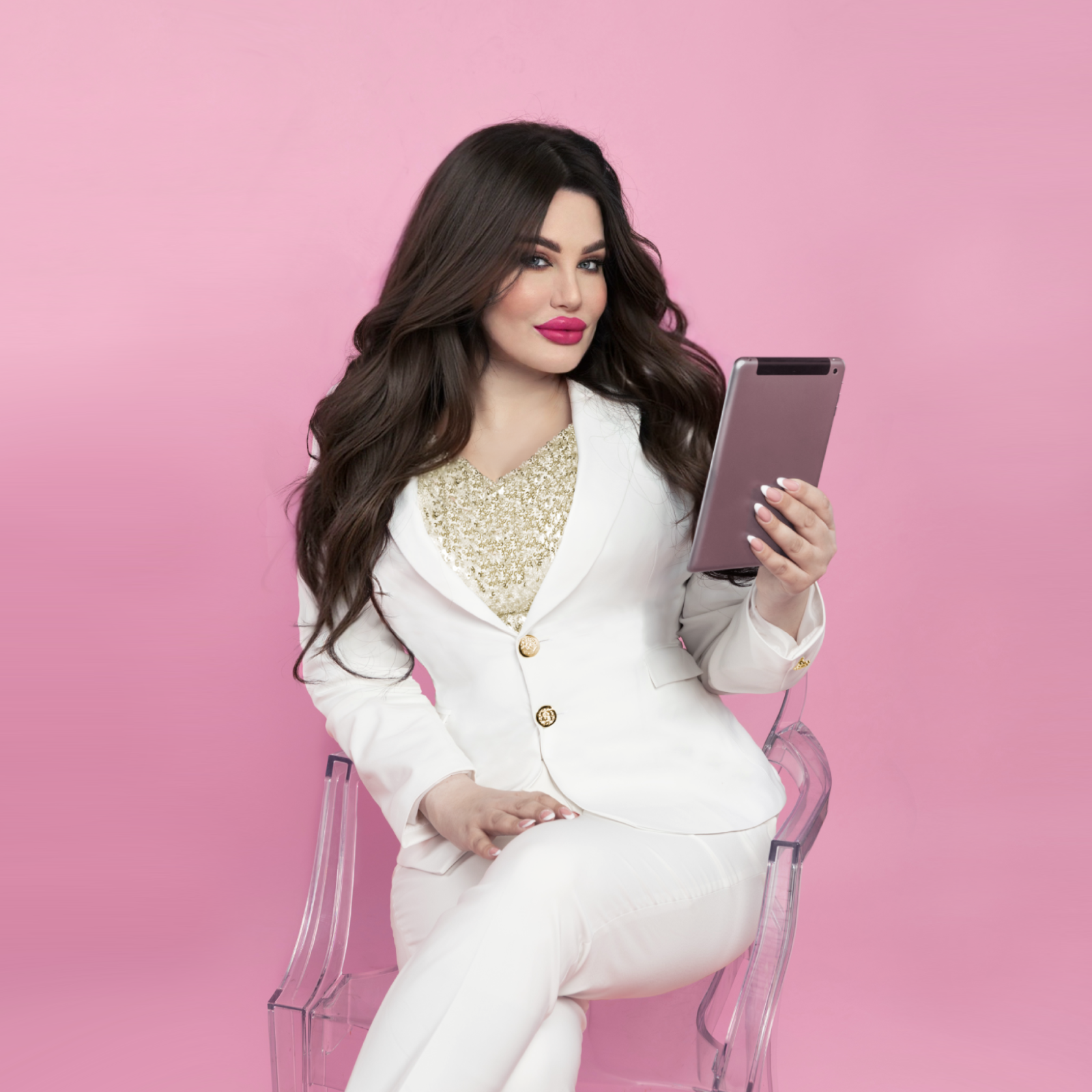 A friendly female relationship coach for women Aneta Mildiani, in a professional white blazer, sits engaged with a tablet, preparing for live workshops. The vibrant pink background highlights community and connection. This photo captures the essence of interactive 'live workshops' designed to empower women with practical tools for healthier, more fulfilling relationships.